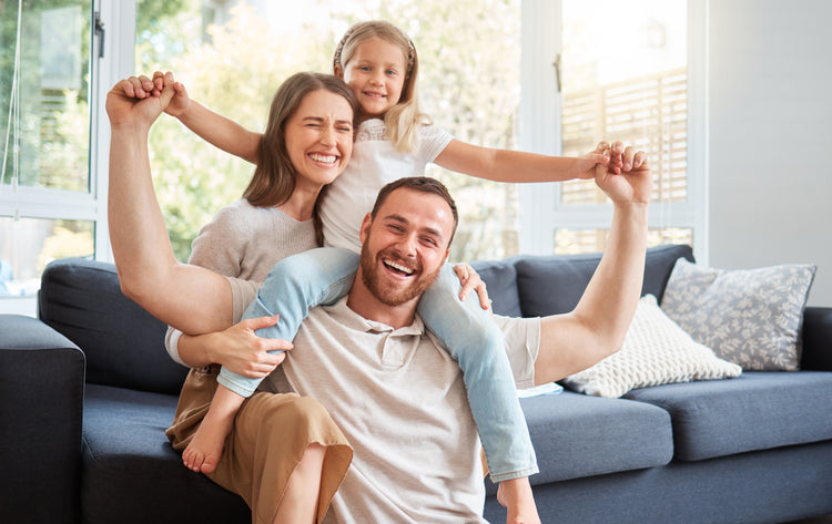 Family of three sitting on a couch in a living room